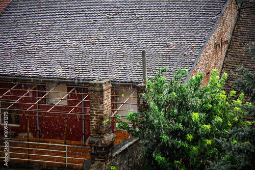 Downpour blurs view of tiled rooftops