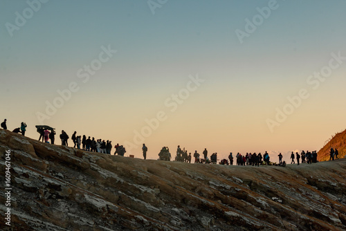 Tourists trek at sunrise along the ridge of the caldera overlooking Kawah Ijen, a turquoise crater lake in the stratovolcano Mount Ijen, located in East Java, a province on Indonesia's Java island