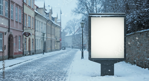 Illuminated blank advertising billboard mockup on a charming, snow-covered European city street during a snowfall