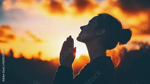 Woman praying at sunset with hands clasped