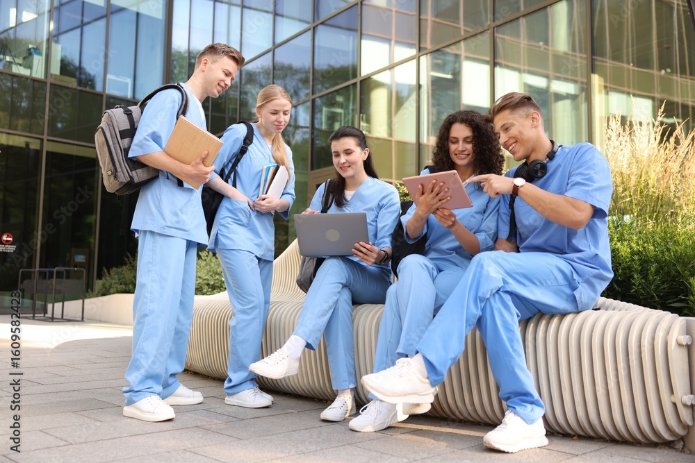 Fototapeta premium Group of medical students in uniforms studying together near building outdoors