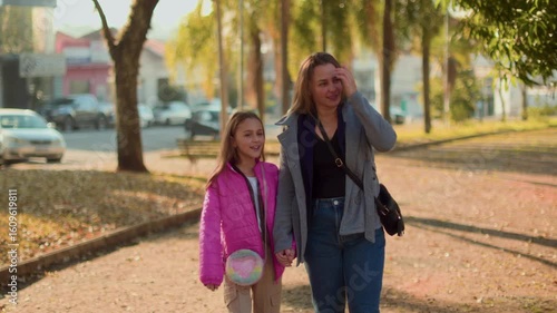 Mother walking with daughter holding hands in the park