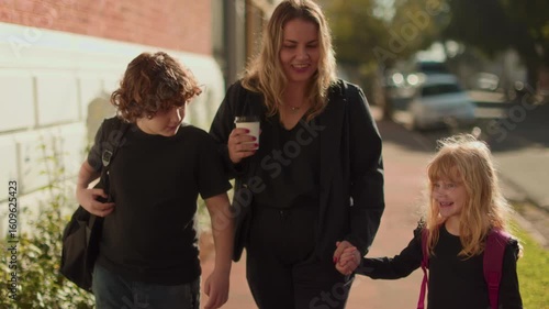 Happy mother walking with children outdoors, family lifestyle moment