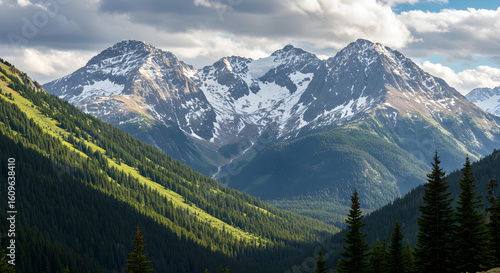 Snowcapped mountains and green forests under a cloudy sky