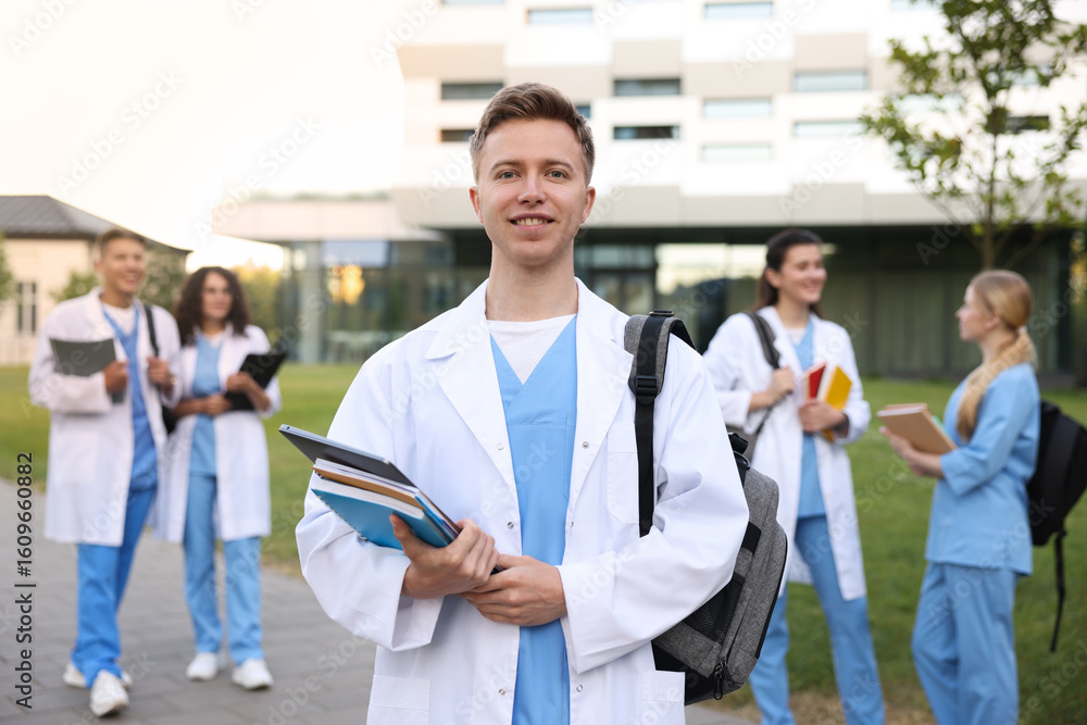 Obraz premium Medical student in uniform with backpack, laptop and notebooks outdoors, selective focus