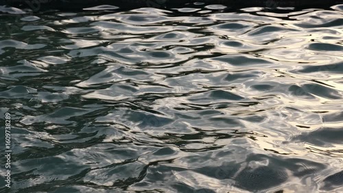 Abstract water surface background: slow motion of liquid in sunset light