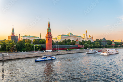 View of Kremlin with Vodovzvodnaya tower, Grand Kremlin Palace from repaired Bolshoy Kamenny Bridge in Moscow city on sunny summer day. Cruise ship sails on the Moscow river
