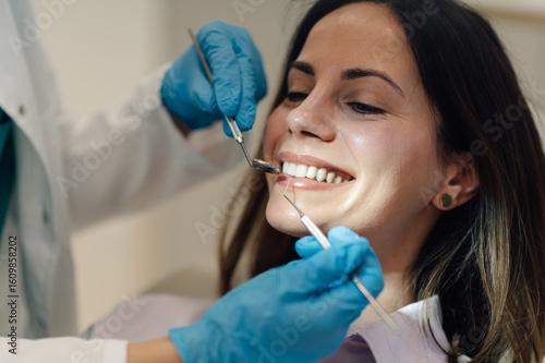 Cuadro en lienzo Dentist examining teeth of smiling female patient in dental clinic