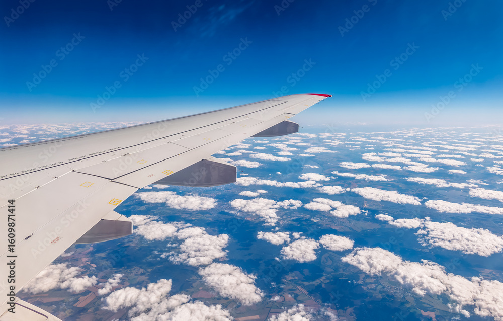 Fototapeta premium View from the airplane window at a beautiful cloudy sky and the airplane wing