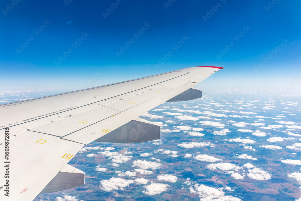 Fototapeta premium View from the airplane window at a beautiful cloudy sky and the airplane wing