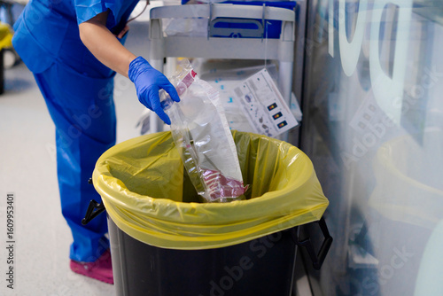 Nurse disposing of medical waste in hospital setting, maintaining hygiene and safety protocols