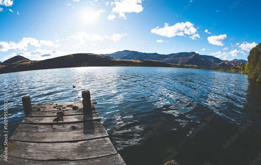 Obraz premium Lake hayes new zealand beautiful water calm nature surrounded by mountains blue clear day sunshine