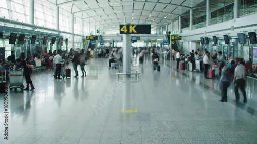 Busy airport terminal bustling with travelers, luggage carts, and digital flight information displays, showcasing the dynamic atmosphere of air travel and movement in a modern setting