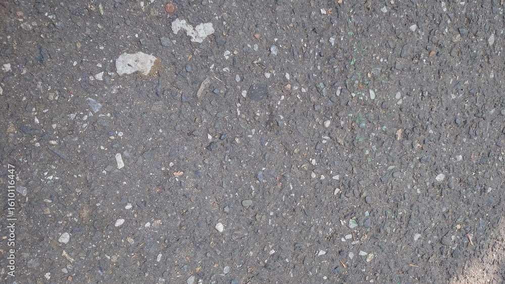 Fototapeta premium Close-up texture of asphalt road surface, ideal for backgrounds, infrastructure themes, or urban design elements. High detail suitable for construction or transport-related visuals.