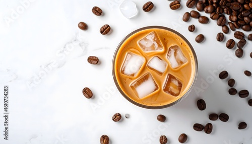 Top view of iced coffee with milk and ice cubes, surrounded by scattered coffee beans on white marble background, minimalist and refreshing beverage concept.