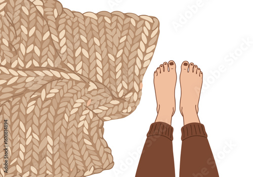 Cozy feet on knitted blanket in warm tones at home  