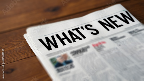 “What’s New?” newspaper title. Close-up shot on a wooden table. News, current events and information concept.