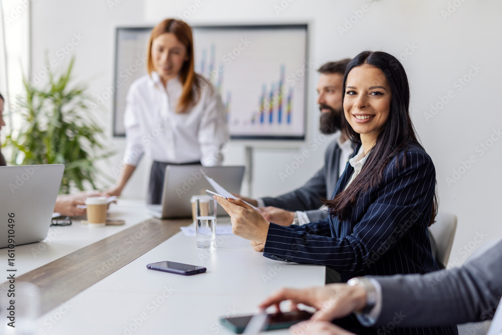 Selective focus on smiling businesswoman with tablet sitting at boardroom with tablet and smiling at camera. Selective focus on smiling businesswoman with tablet sitting at boardroom with tablet and smiling at camera.