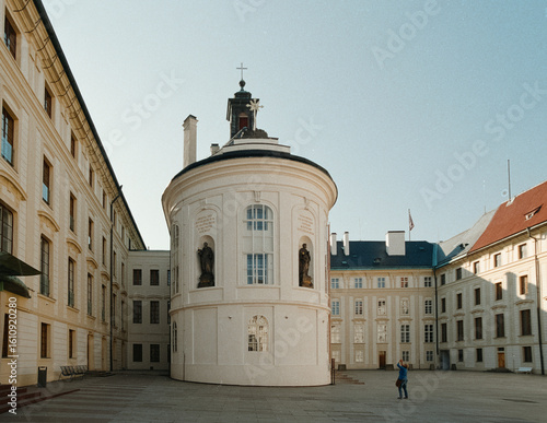 A sunlit analog 35mm film photograph captures the historic Prague Castle courtyard with its distinctive rotunda, devoid of crowds.