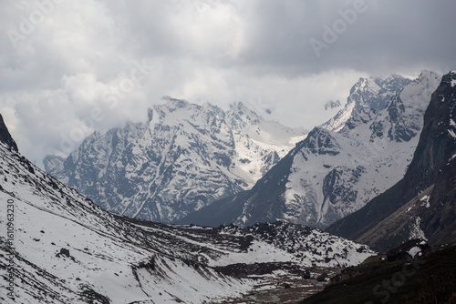 Vast snow-capped Himalayan mountains under an overcast sky in Sikkim, showcasing rugged alpine terrain