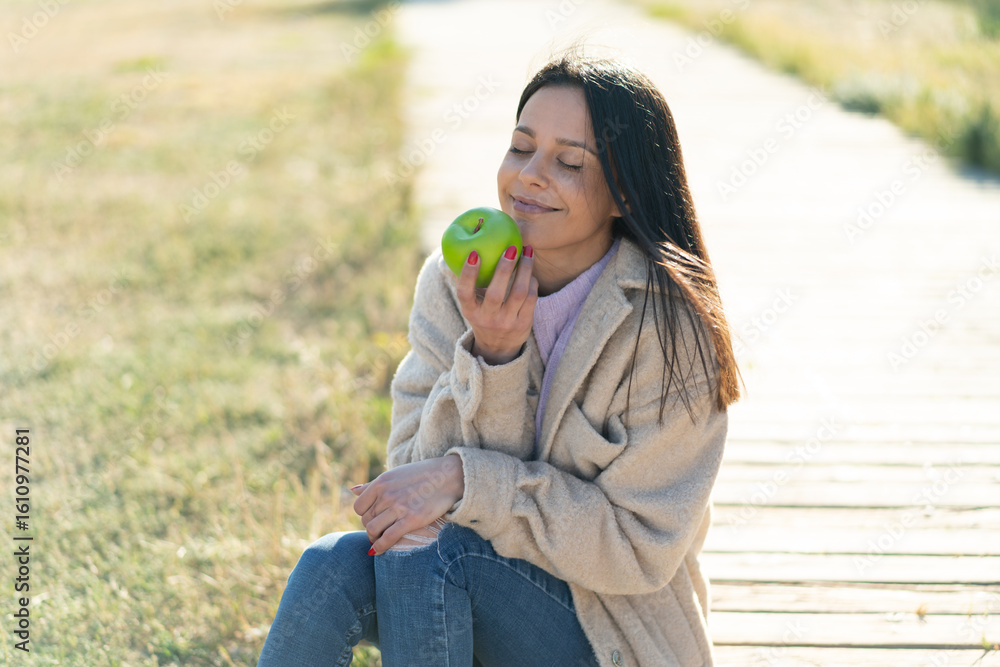 Fototapeta premium Young woman at outdoors holding an apple