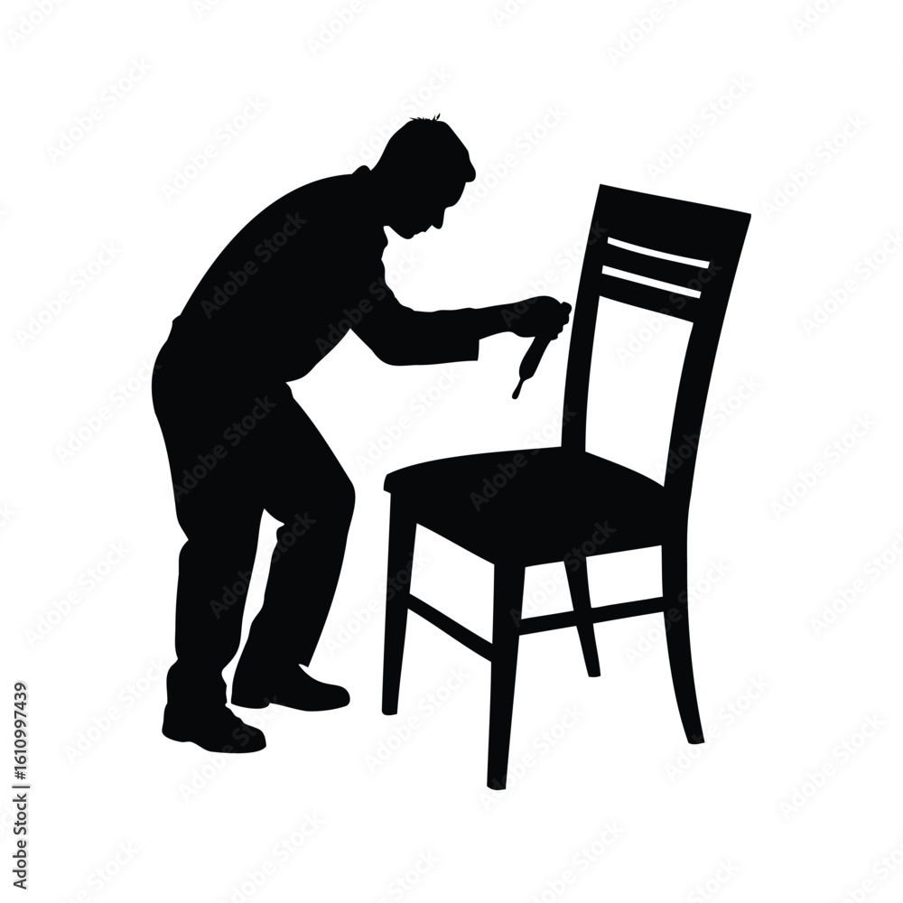 Fototapeta premium Silhouette of a man repairing or painting a chair with a brush