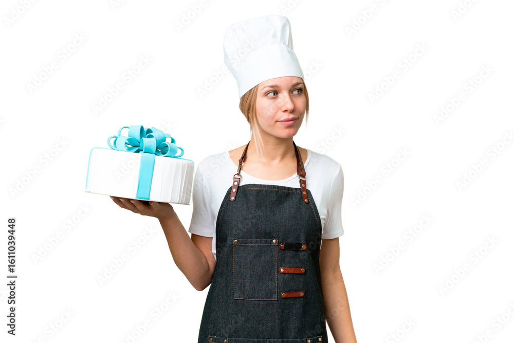 Young pastry blonde woman with a big cake over isolated chroma key background looking to the side Young pastry blonde woman with a big cake over isolated chroma key background looking to the side