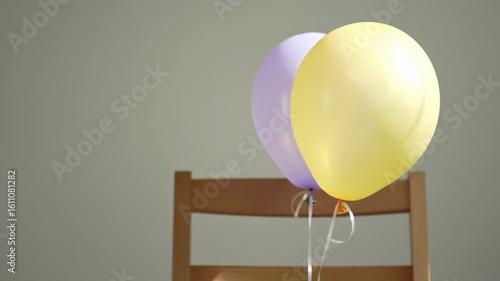 Colorful Balloons Tied to a Wooden Chair in a Bright Room