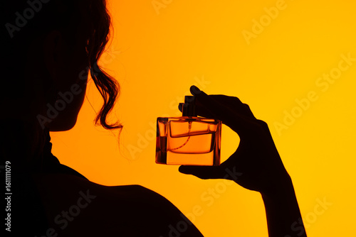 Foto Woman Silhouette Holding Perfume Bottle on Orange Background