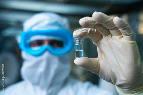liquid injection close up. isolated vaccine vial injection in hand. vaccine shot. background of machine manufacturing a lot of injections in glass ampoule vial in a healthcare pharmaceutical factory.