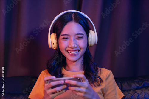Excited Young Asian girl playing an online game on a smartphone on the sofa in the living room.