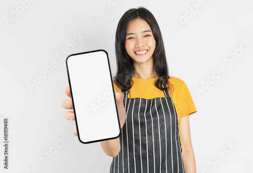 Happy Asian woman owner in black apron standing with holding smartphone on white background.