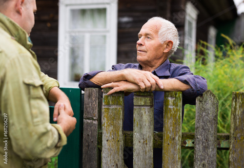 Fotografija Elderly man discussing with neighbour beside house