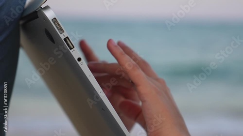 girl typing on laptop. Close-up. Sea in the background. Work by the sea.