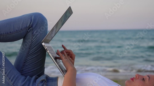 girl with notebook is lying near the sea. work near the sea