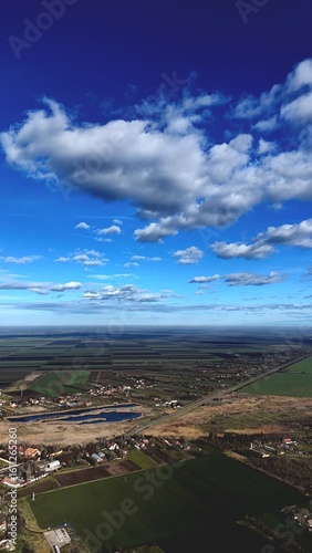  Aerial view of a rural village and farmlands under a dramatic blue sky, Serbia