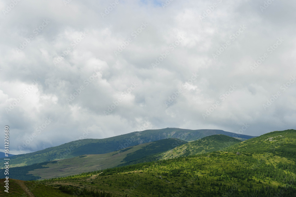 Obraz premium clouds over the mountains hills on layers landscape in summer 