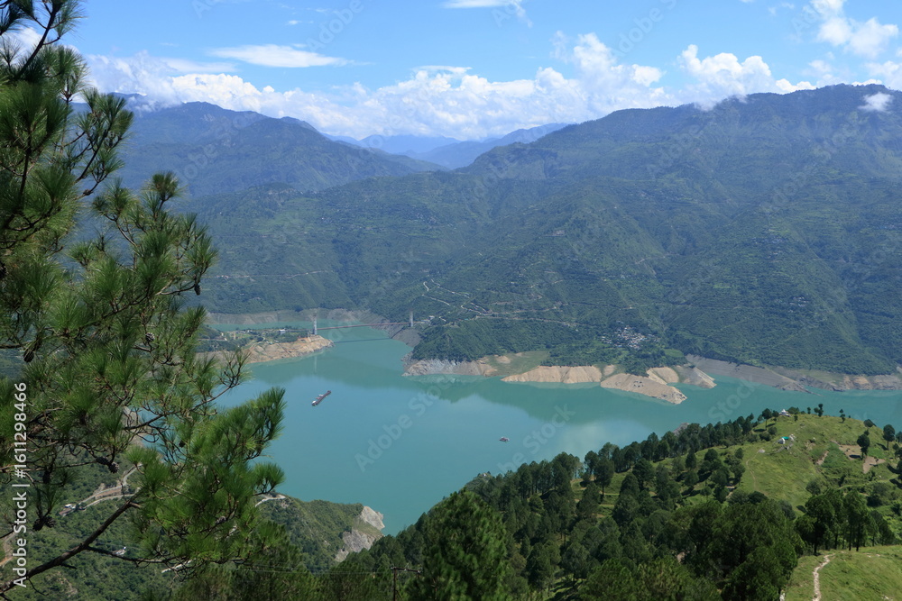 Obraz premium Tehri Lake, nestled in the Garhwal Himalayas of Uttarakhand, is a stunning man-made reservoir created by the Tehri Dam. Surrounded by lush green hills and snow-capped peaks.