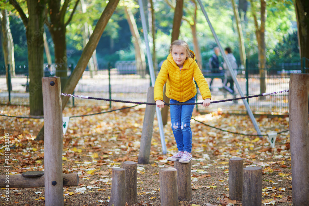 Cheerful little girl having fun on playground in autumn park in Paris, France. Cheerful little girl having fun on playground in autumn park in Paris, France.