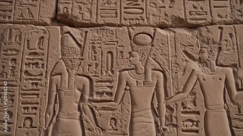 Ancient stone carvings depict figures in traditional attire and hieroglyphs
