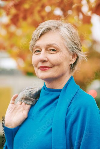 Outdoor autumn close up portrait of beautiful mature woman with grey hair