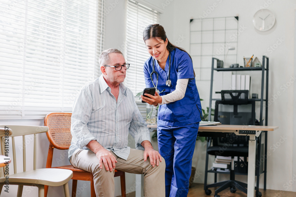Fototapeta premium Happy elderly man at home looking at smartphone together, joyful moment in bright living room, supportive healthcare professional, positive senior care
