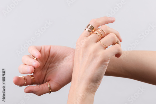 Cuadro en lienzo Female hands with many gold rings on fingers, gray background