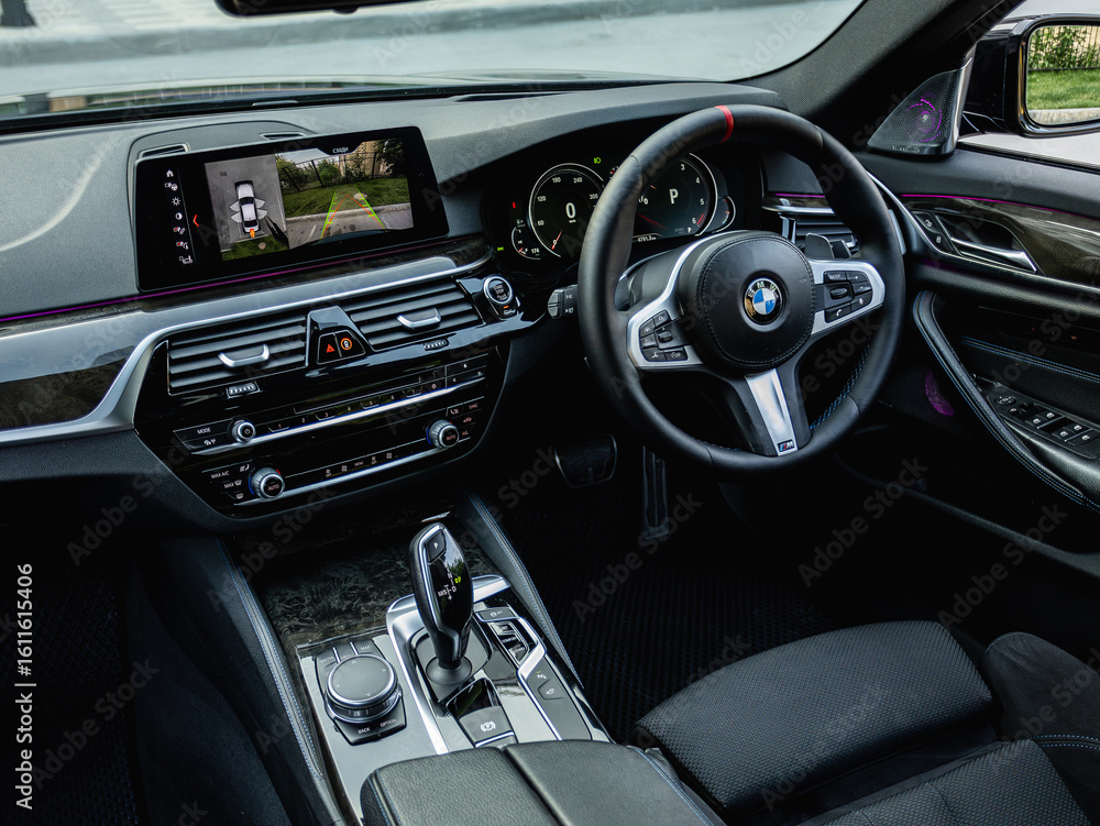 Fototapeta premium Novosibirsk, Russia - July 10, 2024: black BMW 5-series, car Interior - steering wheel, shift lever and dashboard, climate control, speedometer, display