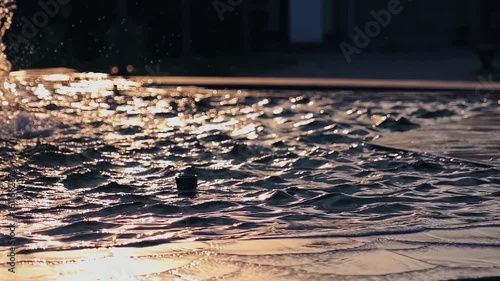 Abstract water surface background: slow motion of water waves in fountain with bokeh during sunset
