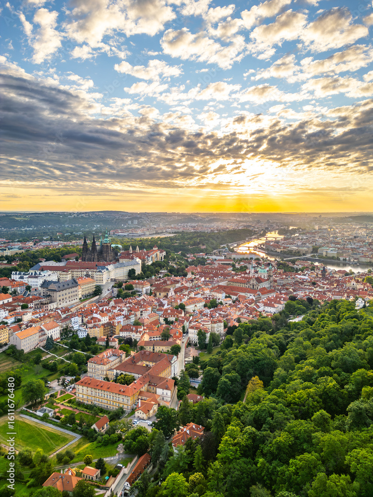 Obraz premium At sunrise, the stunning Prague Castle overlooks the city, with its impressive architecture illuminated by soft golden rays. The tranquil river and vibrant rooftops create a picturesque view.