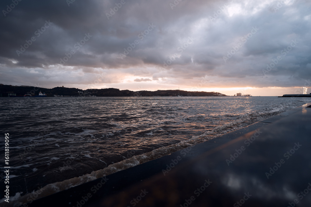 Fototapeta premium A dramatic seascape at sunset with dark clouds and choppy waves.