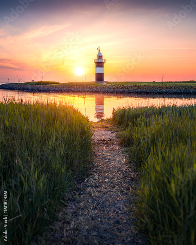 Sonnenuntergang an einem kleinen Leuchtturm an der deutschen Nordseeküste.