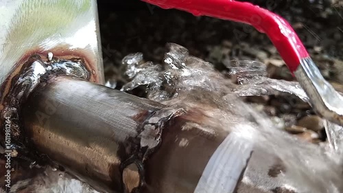 A steady stream of water pours from ametal tap with a bright red lever handle. Simple, utilitarian scene capturing the function of plumbing and the essential flow of fresh water.