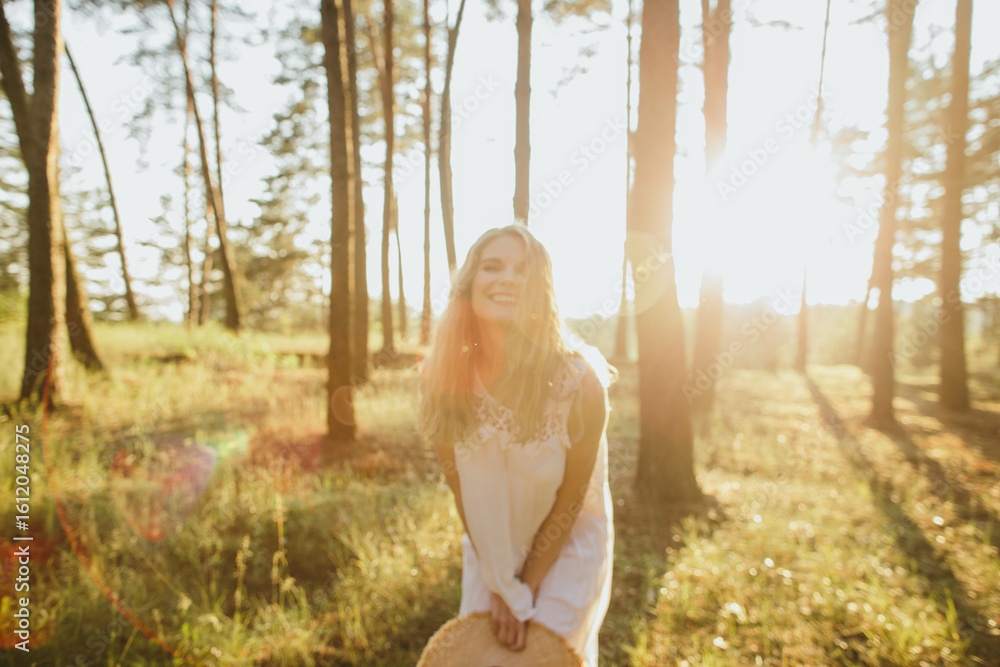 Naklejka premium Happy woman enjoying sunlight in forest at sunset